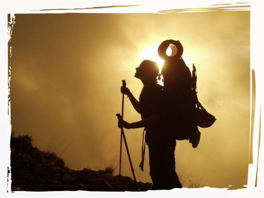 Person trekking with sun behind them