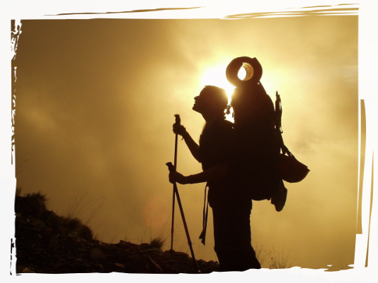 Trekking with rucksack Person trekking with sun behind them