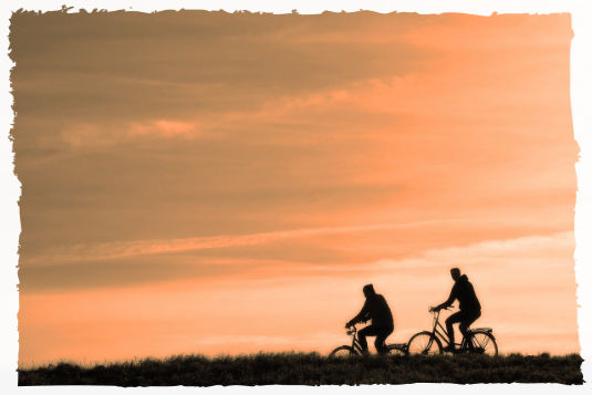 Cycling Two people cycling at sunset